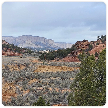 Photograph of a scenic valley with sandstone formations in the background.